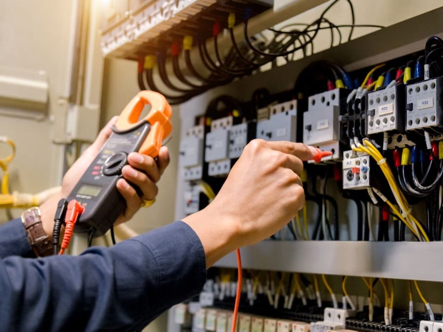 Electricista midiendo con pinza amperométrica en un tablero eléctrico